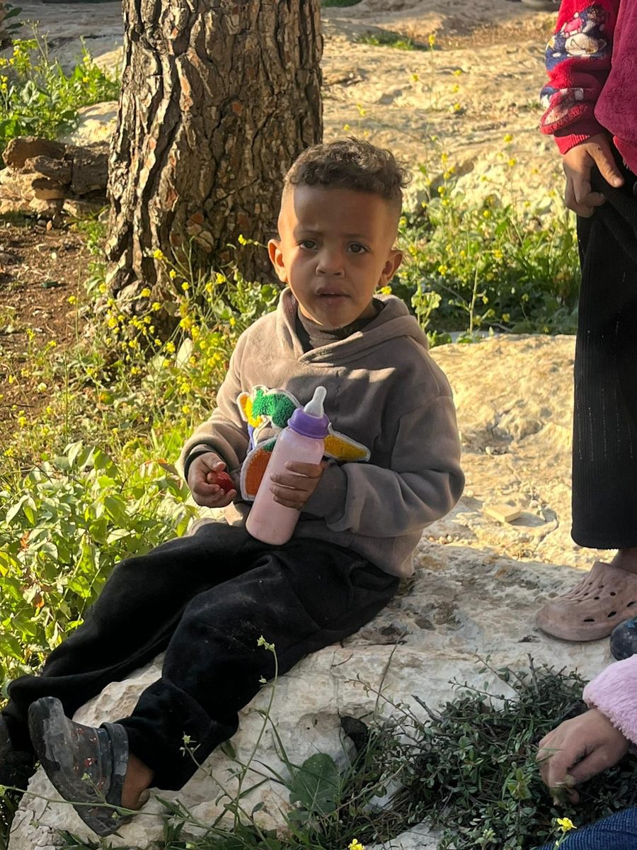Displaced child sitting outdoors