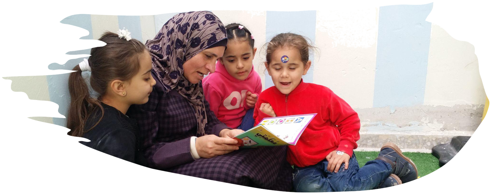 A mother reading with three children at Al Tafawk Children's Centre